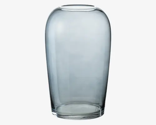 Klar glasvase med en glat, afrundet cylindrisk form, der bliver en smule smallere foroven. Vasen har en bred åbning og en tyk, solid bund, hvilket giver den et moderne og minimalistisk udtryk. Glasset er gennemsigtigt med et diskret gråt skær.