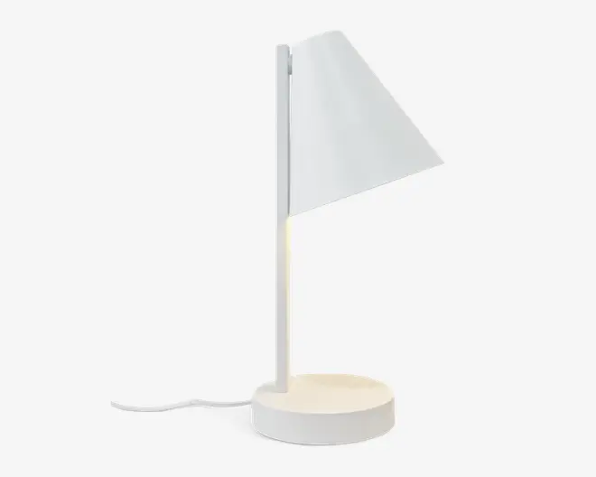 Minimalistisk hvid lampe med rund fod og slank, lodret stang. Lampen har en unik trekantet skærm, der leder lyset nedad og giver et fokuseret lys. Strømledningen går ud fra bunden, og det samlede design er stilrent og moderne, velegnet til nutidige indretninger.