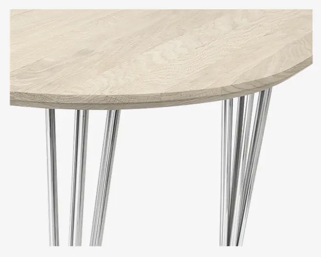 Nærbillede af et bord med en rund bordplade i lyst træ med naturlig årestruktur. Bordet har flere slanke, skråtstillede ben i blankt krom, hvilket giver det et moderne og minimalistisk udtryk.