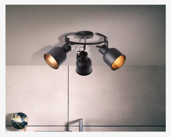 Loftmonteret lampearmatur med tre justerbare spotlys i mat sort metal, arrangeret i en cirkulær formation. Hver spot har en bred, konisk skærm med gylden inderside, der giver et varmt lys. Armaturet er fastgjort til en rund base og har industrielle detaljer for et moderne og funktionelt udtryk.