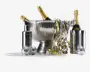 Billedet viser en festlig opstilling med en stor, riflede isspand i rustfrit stål, der indeholder flasker champagne. Rundt om spanden står en elegant metalcocktailshaker, en høj cylindrisk vinkøler og flere små diskokugledekorationer. Guld- og hvide krøllede bånd er draperet over spanden og spredt på bordet, hvilket understreger den festlige stemning. Udtrykket er elegant og klar til fest med fokus på metalliske overflader og glitrende detaljer.