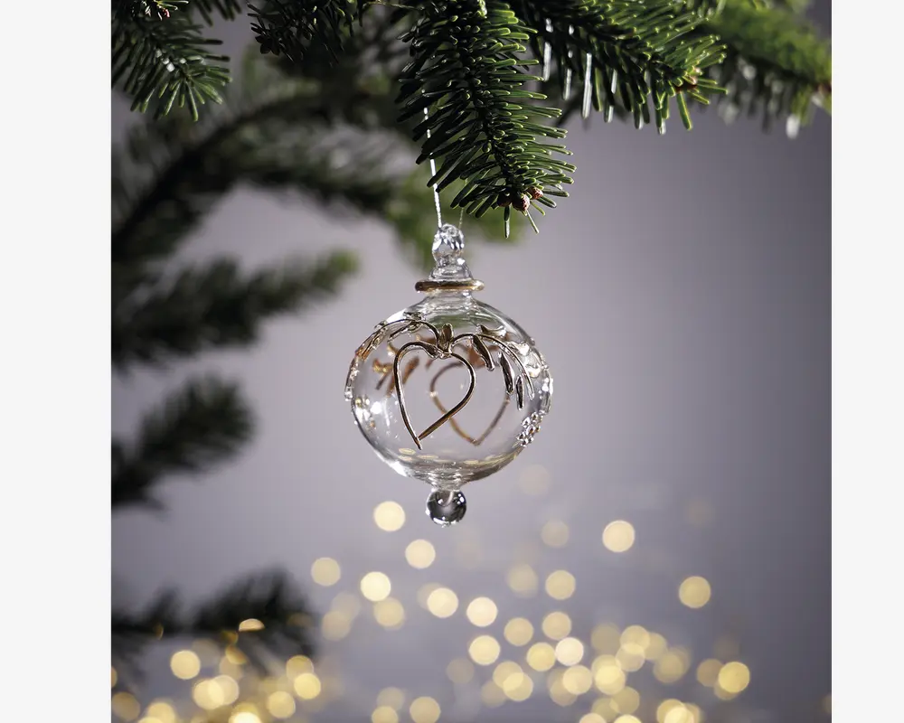 Klar glaskugle med et fint guldfarvet hjerte-design indeni, toppet med en lille glasfinial og ophæng. Kuglen er rund og har en lille glasperle i bunden, hvilket giver et elegant og festligt udtryk.