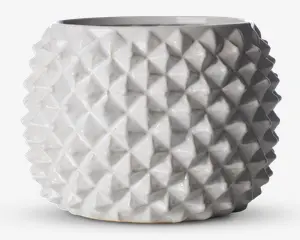 En rund, hvid keramisk beholder med blank overflade og et markant geometrisk mønster. Overfladen er dækket af gentagne, opadstående pyramideformede knopper, hvilket giver et moderne og taktilt udtryk. Åbningen foroven er bred, og formen er let tilspidset mod bunden.