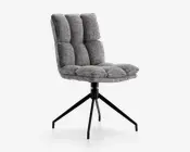 En moderne stol med en blød, polstret sæde og ryglæn betrukket med tekstureret gråt stof. Stolen har en komfortabel, vatteret udformning med dybe vandrette og lodrette syninger, der giver et quiltet udseende. Den står på en solid sort metalbase med fire skråtstillede ben for stabilitet og et moderne udtryk.