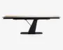 Rektangulært bord med en lys træbordplade og en moderne, skråtstillet sort sokkel. Bordpladen ser ud til at kunne forlænges, da der er synlige samlinger, der indikerer udtræksplader. Basen er en enkelt, solid støtte med et geometrisk design, som giver stabilitet og et moderne udtryk.