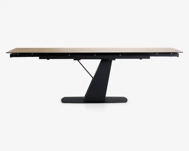 Rektangulært bord med en lys træbordplade og en moderne, skråtstillet sort sokkel. Bordpladen ser ud til at kunne forlænges, da der er synlige samlinger, der indikerer udtræksplader. Basen er en enkelt, solid støtte med et geometrisk design, som giver stabilitet og et moderne udtryk.