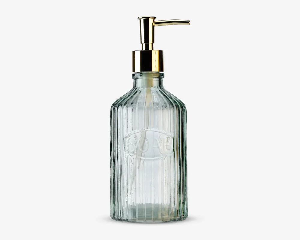 Dispenserflaske i klart glas med lodret rillet struktur, udstyret med en guldfarvet pumpe og et ovalt, hævet mærke på forsiden med ordet 'SOAP' præget. Flasken har et vintage-inspireret design og en solid bund.