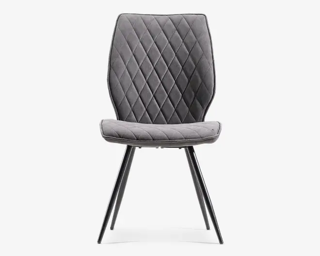 Grå polstret stol med buet ryglæn med diamantquiltning, blødt sæde og slanke sorte skrå ben.