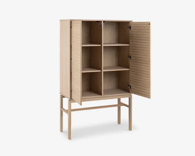 Højt skab i lyst træ med fire slanke ben. Skabet har to låger med vandrette riller og åbnes op til fire rummelige rum, adskilt af to lodrette og én vandret hylde. Indersiden har samme lyse træfinish som ydersiden, og designet er minimalistisk og moderne.