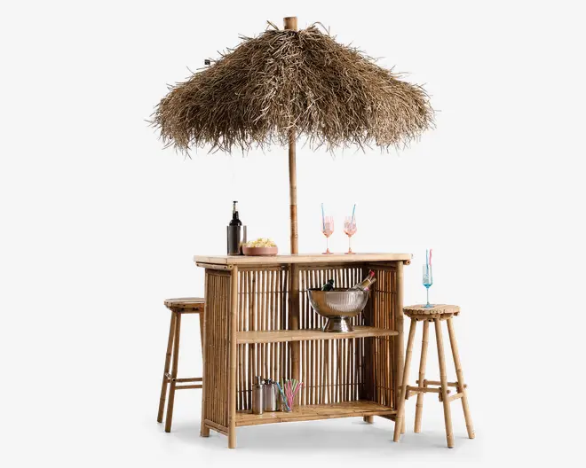 Udendørs barsæt fremstillet i naturlig bambus med et stråtag som parasol for skygge. Baren har to matchende bambusbarstole og åbne hylder til opbevaring, hvor der blandt andet står en metal isspand, cocktailshakere og glas. Designet har et tropisk, strandinspireret udtryk, perfekt til udendørs underholdning.