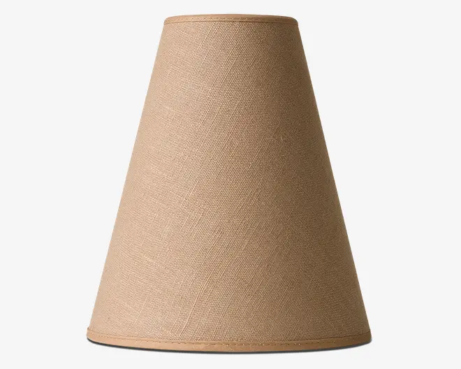Konisk lampeskærm med et naturligt beige stof på ydersiden. Overfladen har en diskret vævet struktur, og kanterne er pænt afsluttet med matchende kantbånd foroven og forneden. Skærmen er designet til at give et blødt lys og passer til standard lampesokler.