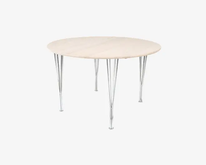 Rundt bord med en lys træbordplade og karakteristiske ben i krommetal. Benene er tynde, skråtstillede og samlet i par, hvilket giver et moderne og let udtryk. Bordpladen har en glat, naturlig finish.