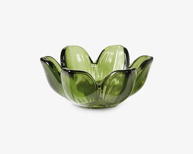 Grøn glasskål med et kronbladsformet design, bestående af seks afrundede, opadbuede sektioner, der ligner blomsterblade. Glasset er gennemsigtigt med en blank overflade, hvilket giver skålen et dekorativt og elegant udtryk.