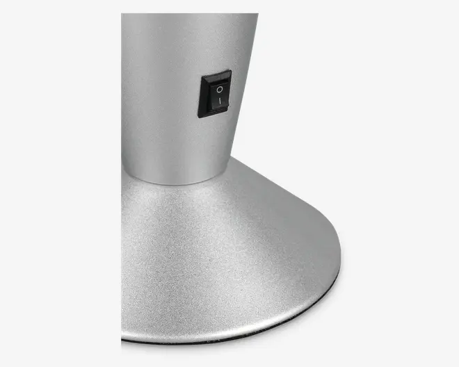 Nærbillede af en mat sølvfarvet base med en sort tænd/sluk-vippeknap placeret på den lodrette del. Basen er bred og stabil, hvilket giver god støtte til den øvre del af enheden.
