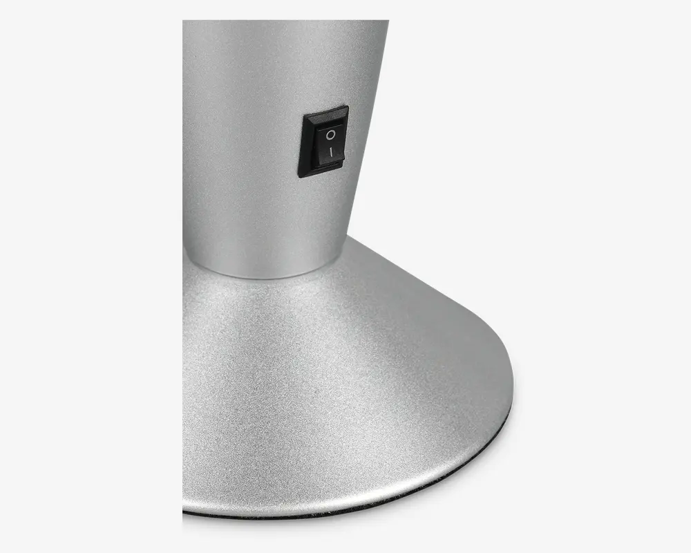 Nærbillede af en mat sølvfarvet base med en sort tænd/sluk-vippeknap placeret på den lodrette del. Basen er bred og stabil, hvilket giver god støtte til den øvre del af enheden.