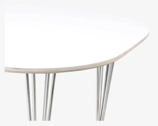 Nærbillede af et bordhjørne med en glat, hvid bordplade og let afrundet kant. Bordet har flere slanke, sølvfarvede metalben, der er vinklet og placeret i et moderne design for ekstra stabilitet og et stilfuldt udtryk.