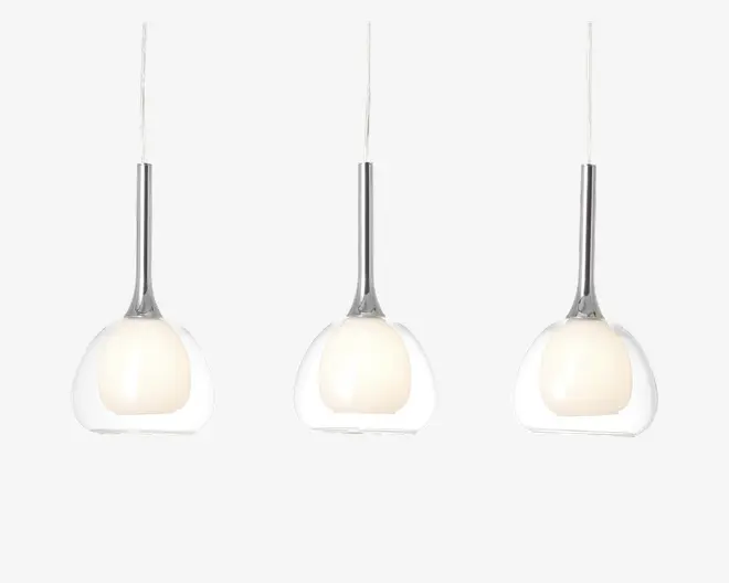 Sæt med tre pendellamper med ydre skærme af klart glas og indre kugler af mat glas. Hver lampe hænger fra en slank, metallisk stang, hvilket giver et moderne og elegant udtryk. De matte indre kugler spreder lyset blødt, mens det gennemsigtige ydre lag tilføjer et stilrent, nutidigt præg.