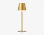Elegant, moderne lampe med mat guld-finish. Lampen har en konisk lampeskærm, en slank cylindrisk stang og en flad, rund fod. Designet er minimalistisk og stilfuldt, velegnet til moderne indretning.