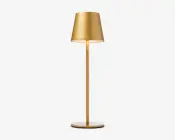 Elegant, moderne lampe med mat guld-finish. Lampen har en konisk lampeskærm, en slank cylindrisk stang og en flad, rund fod. Designet er minimalistisk og stilfuldt, velegnet til moderne indretning.