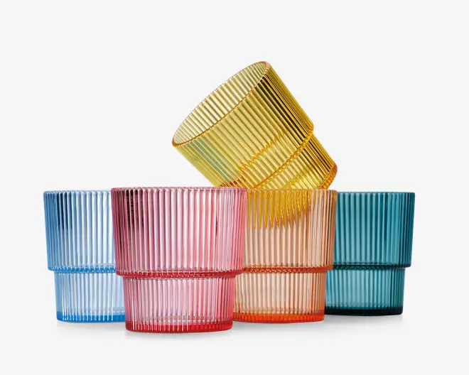 Sæt med seks lave, brede drikkeglas i forskellige gennemsigtige farver: lyseblå, pink, gul, orange og turkis. Hvert glas har en lodret rillet struktur på ydersiden, hvilket giver dem et moderne og stilfuldt udseende. Glassene kan stables og har en tyk, solid bund.