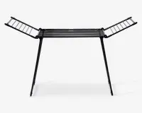 Et sammenklappeligt tørrestativ lavet af metal med sort finish. Det har en central sektion med parallelle stænger til at lægge tøj fladt, samt to sidevinger, der kan foldes ud for ekstra hængeplads. Stativet står på to skrå ben for stabilitet og kan foldes sammen for nem opbevaring.