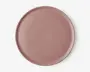 En rund, flad tallerken med en glat, mat overflade i en afdæmpet støvet rosa farve. Tallerkenen har en let hævet kant og et minimalistisk, moderne design uden mønstre eller dekorationer.
