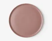 En rund, flad tallerken med en glat, mat overflade i en afdæmpet støvet rosa farve. Tallerkenen har en let hævet kant og et minimalistisk, moderne design uden mønstre eller dekorationer.