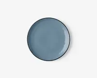 Rund keramiktallerken med en glat, blank overflade i en afdæmpet blå farve. Tallerkenen har en let hævet kant og et minimalistisk, moderne design uden mønstre eller dekorationer.