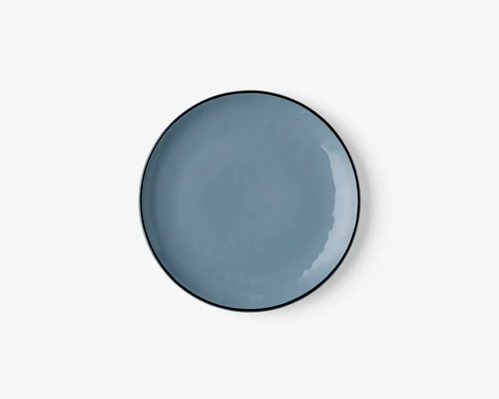 Rund keramiktallerken med en glat, blank overflade i en afdæmpet blå farve. Tallerkenen har en let hævet kant og et minimalistisk, moderne design uden mønstre eller dekorationer.