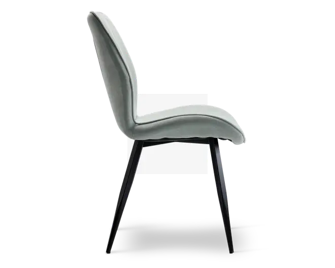 Sidevisning af en moderne stol med let buet, polstret ryglæn og sæde betrukket med et blødt, lysegråt stof. Stolen har slanke, skråtstillede sorte metalben, der giver et stilrent og minimalistisk udtryk. Sæde og ryglæn er sømløst forbundet og giver ergonomisk støtte samt et moderne design.