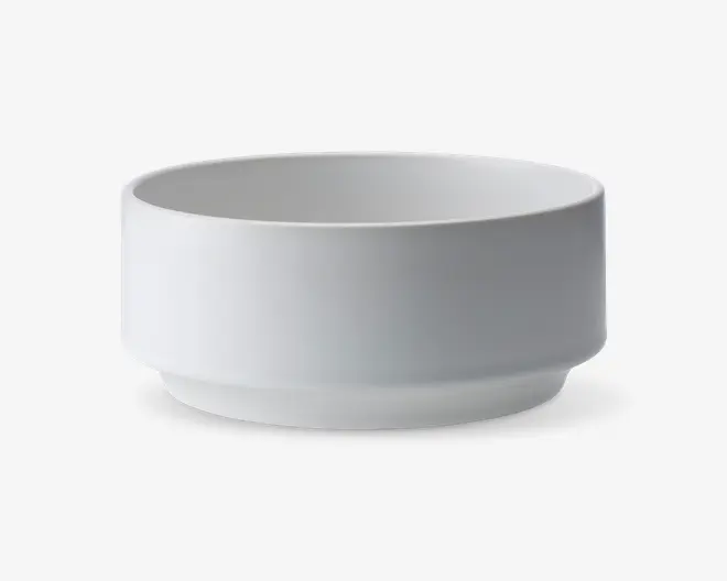 En minimalistisk, rund skål med lige sider og flad bund, lavet af glat hvid keramik. Skålen har et moderne, enkelt design uden mønstre eller dekorationer og en let hævet fod for stabilitet.