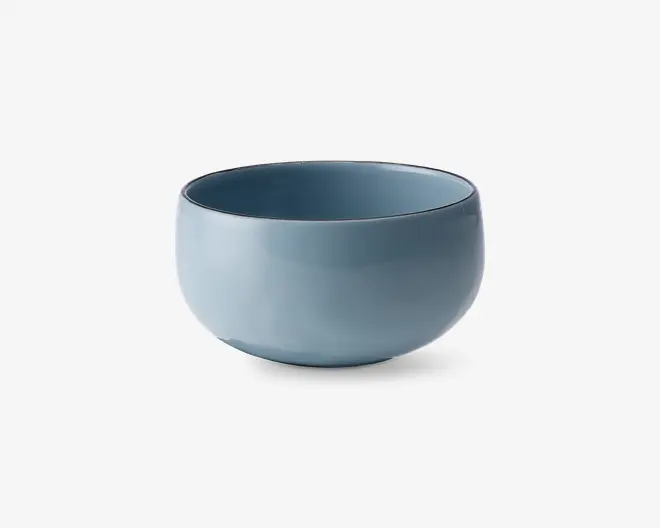 En rund, glat skål med mat blå finish. Skålen har et enkelt, minimalistisk design med blødt buede sider og en let tyk kant. Både indersiden og ydersiden er ensfarvet, hvilket giver et moderne og elegant udtryk.
