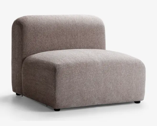 Armløs loungestol med et minimalistisk, moderne design, der har et tykt, rektangulært sæde og en afrundet ryglæn. Stolen er polstret med et tekstureret, lysebrunt stof og har en lav profil samt et blødt, polstret udseende for komfortabel siddeoplevelse.
