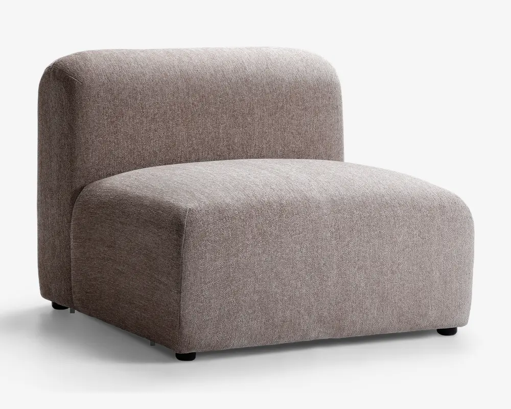 Armløs loungestol med et minimalistisk, moderne design, der har et tykt, rektangulært sæde og en afrundet ryglæn. Stolen er polstret med et tekstureret, lysebrunt stof og har en lav profil samt et blødt, polstret udseende for komfortabel siddeoplevelse.