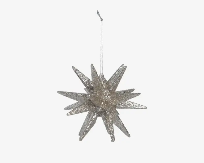 Et tredimensionelt stjerneformet ornament med flere spidse takker, dækket af sølvglimmer for en glitrende effekt. Den har en løkke øverst til ophængning, hvilket gør den velegnet til at pynte træer eller festlige dekorationer.