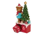 En dekorativ julefigur med en bamse iført rød nissehue, rød tørklæde og blå sweater, der står ved siden af et juletræ pyntet med røde kugler og en guldfarvet stjerne i toppen. Bamsen og træet står på en rød base med hvide "sne"-detaljer. Basen har to røde terninger med tal og en plads til at ændre datoen, hvilket gør det til en nedtællingskalender. Der er også små, farverige gaver ved træets fod.