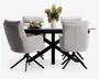 Sæt med fire moderne spisebordsstole betrukket med lysegråt stof, med høje rygge, polstrede sæder og armlæn for ekstra komfort. Hver stol har en sort metal-dreje-fod med fire skrå ben. Stolene er placeret omkring et rektangulært spisebord med hvid bordplade og sorte metalben. Bordet er pyntet med en lyserød vase med blomster, to vinglas og en tallerken med snacks.