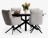 Sæt med fire moderne spisebordsstole betrukket med lysegråt stof, med høje rygge, polstrede sæder og armlæn for ekstra komfort. Hver stol har en sort metal-dreje-fod med fire skrå ben. Stolene er placeret omkring et rektangulært spisebord med hvid bordplade og sorte metalben. Bordet er pyntet med en lyserød vase med blomster, to vinglas og en tallerken med snacks.