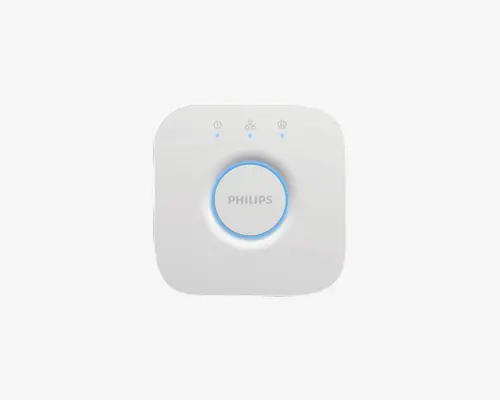 En kompakt, firkantet hvid enhed med afrundede hjørner. Den har en stor, cirkelformet knap i midten med en blå LED-ring omkring og Philips-logoet trykt på knappen. Over knappen er der tre små LED-indikatorlys, hver med et forskelligt ikon, der angiver forskellige statusser eller funktioner. Designet er minimalistisk og moderne.