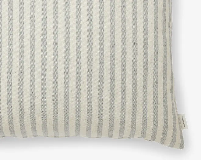 Firkantet pude med betræk, der har lodrette striber i lysegrå og råhvid. Stoffet ser vævet ud og har en let tekstur. Der er et lille stofmærke i sidesømmen. Designet er enkelt og klassisk, hvilket passer til mange forskellige boligindretninger.