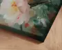 Nærbillede af et lærredsprint med et håndmalet blomsterdesign. Kunstværket viser en stor, blød rosa og hvid blomst med gule og orange detaljer i midten, omgivet af grønne blade og abstrakte penselstrøg i grønne, turkise og rødlige nuancer. Lærredet har en kant, der er foldet om rammen, hvilket giver et moderne og færdigt udtryk.