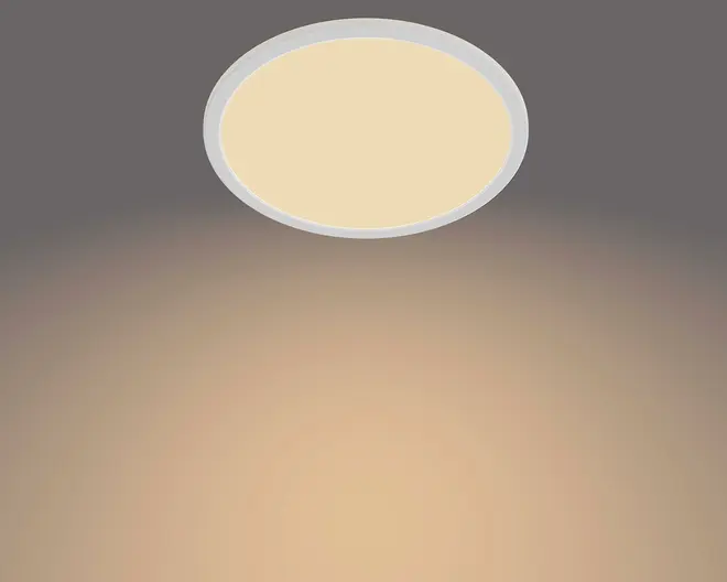 Rund loftlampe til plan montering med slank hvid kant og opal diffuser, der giver et blødt varmt skær på loftet.
