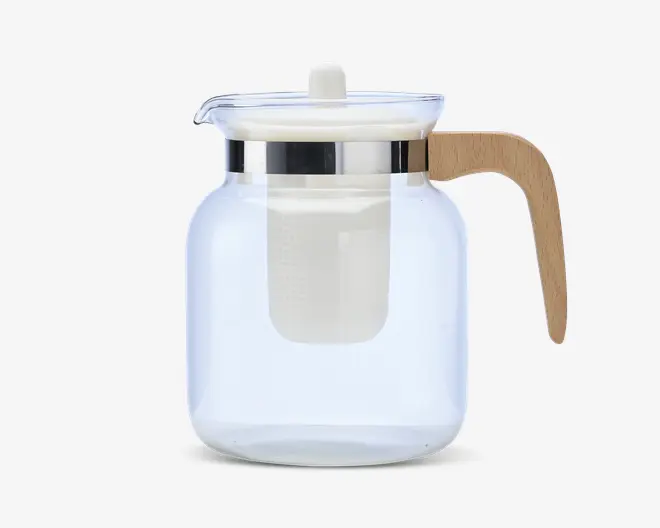 Klar glaskande med bred cylindrisk krop, udstyret med et aftageligt hvidt filter til løs te eller kaffe. Låget er gennemsigtigt med en lille knop øverst, og kanden har en blank metalring omkring halsen. Håndtaget er lavet af lyst træ og er ergonomisk formet for et behageligt greb.