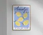Indrammet kunsttryk med en legende illustration af fem gule citroner med grønne blade på en blå og hvidstribet baggrund. Øverst står ordet 'Amalfi' med store, blå, kursiverede bogstaver, og nederst ses sætningen 'il dolce far niente' med mindre håndskrift. Stilen er moderne og minimalistisk med en glad og sommerlig stemning.