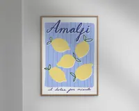 Indrammet kunsttryk med en legende illustration af fem gule citroner med grønne blade på en blå og hvidstribet baggrund. Øverst står ordet 'Amalfi' med store, blå, kursiverede bogstaver, og nederst ses sætningen 'il dolce far niente' med mindre håndskrift. Stilen er moderne og minimalistisk med en glad og sommerlig stemning.