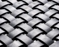 Nærbillede af et vævet mønster lavet af brede, mat sorte strimler. Strimlerne er flettet sammen i et over-under mønster, hvilket skaber en tekstureret, kurvelignende overflade. Materialet virker robust og let tekstureret med en diskret glans på overfladen.