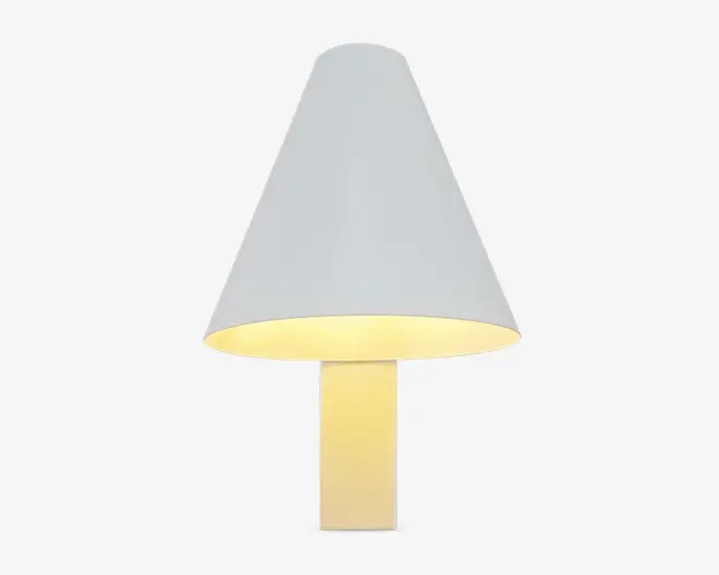 En moderne lampe med et minimalistisk design, der har en stor, kegleformet hvid lampeskærm og en rektangulær, lys base. Lampen udsender et varmt, blødt lys under skærmen, hvilket skaber en hyggelig stemning. De rene linjer og enkle geometriske former giver lampen et moderne udtryk, der passer til forskellige indretninger.