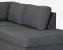 Nærbillede af en mørkegrå polstret sofa med bred sædehynde, tre bløde ryghynder og rene, lige kanter.