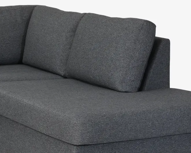 Nærbillede af en mørkegrå polstret sofa med bred sædehynde, tre bløde ryghynder og rene, lige kanter.