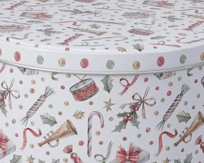 Rund beholder med hvid baggrund, dekoreret med festlige julemotiver såsom sukkerstokke, kristtjørnblade, indpakkede gaver, trommer, trompeter, stjerner og julesprællemænd. Designet har røde, grønne og gyldne detaljer samt små prikker over det hele. Låget sidder tæt og har samme dekorative mønster som beholderen.